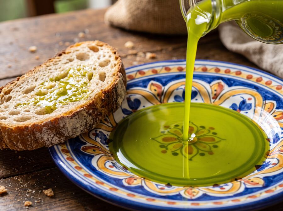 Olio versato su un piatto in ceramica accanto a una fetta di pane